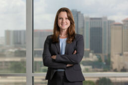 Attorney headshot of female lawyer with her arms crossed and Tampa skyline.