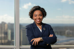 Attorney headshot, female lawyer with arms crossed and Tampa skyline in the background.