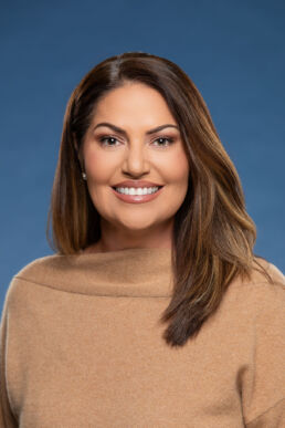 Professional business headshots Tampa, portrait of female staff member against a blue background.