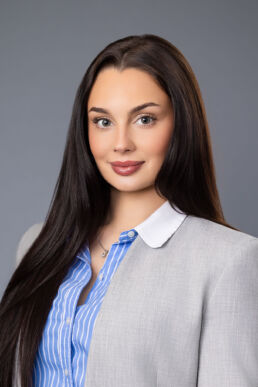 Professional business portrait of female employee against gray background onsite at client office in Tampa, Florida.