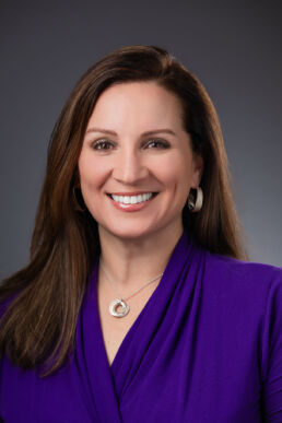 Executive headshot of female executive in studio setting with gray background on location in St. Petersburg Florida.