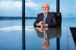 Executive portrait on location of attorney sitting at conference room table with cigar in hand overlooking Tampa Bay.