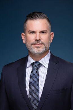 Headshot of executive leadership team member against dark blue background on site in Tampa, Florida.