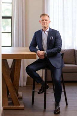 On-location executive portrait of male in blue suit sitting at wooden table in Tampa, Fl.