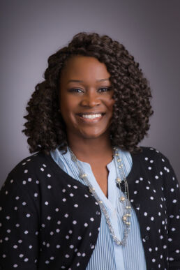 Professional staff headshot of young woman in studio setting against a gray backdrop.