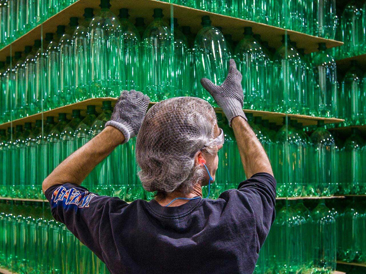 Commercial photo of production facility worker stacking green 2 liter bottles at Origlio Beverage in Philadelphia, PA.