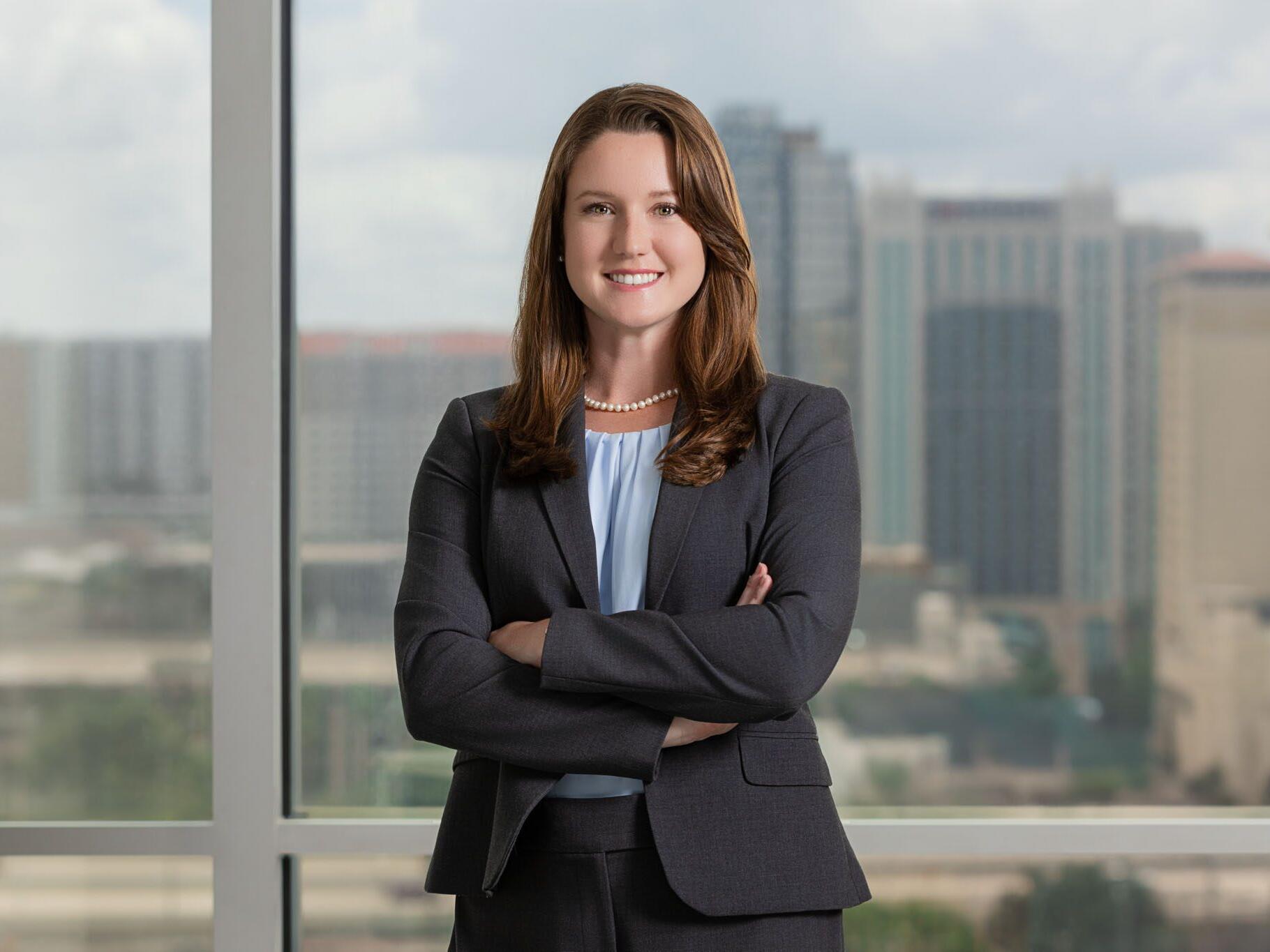 Attorney headshot of female lawyer with her arms crossed and Tampa skyline.