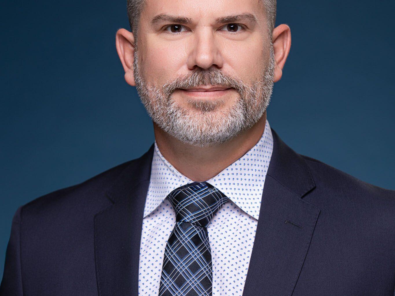 Headshot of executive leadership team member against dark blue background on site in Tampa, Florida.