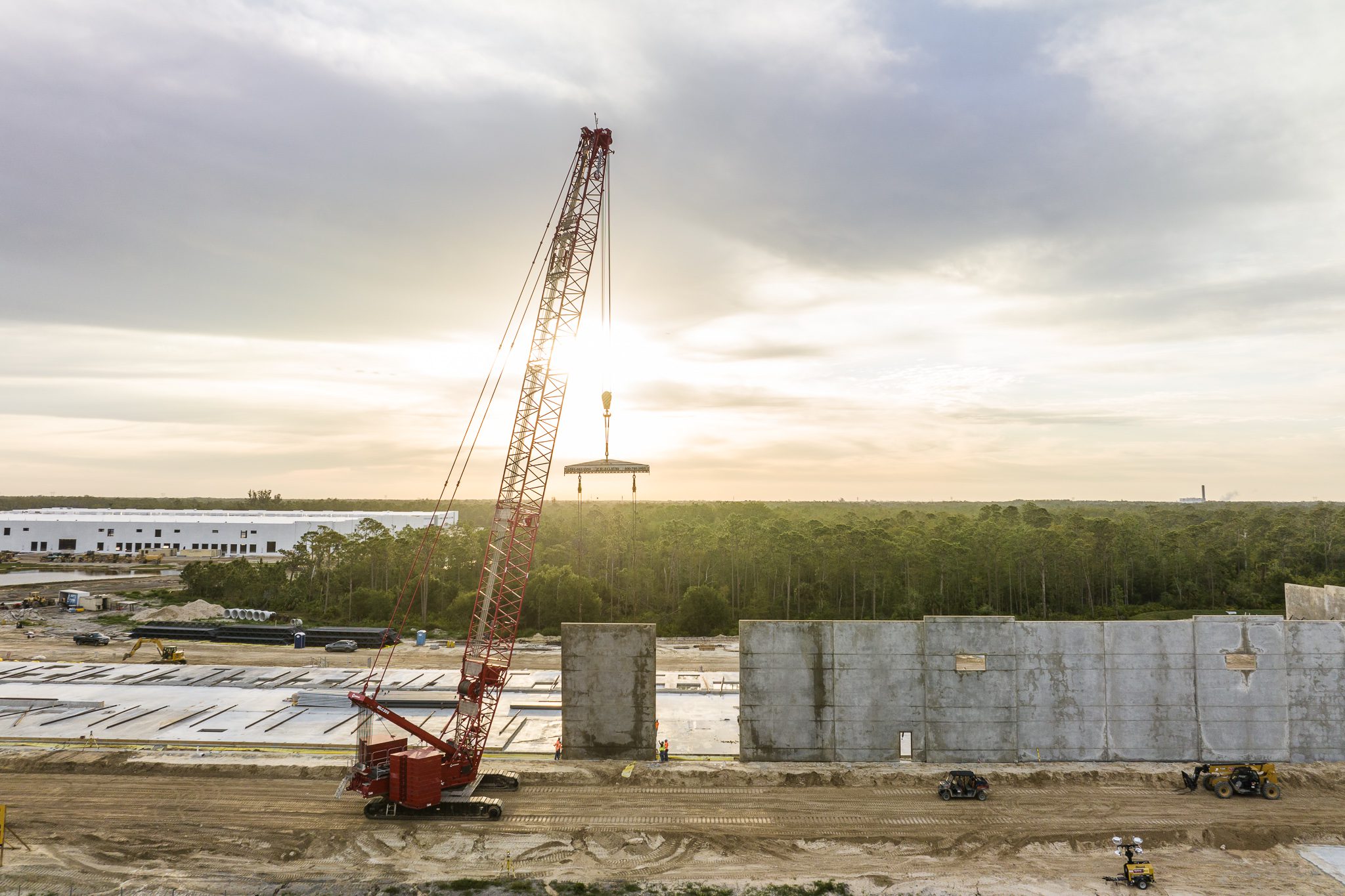 Drone industrial photography capturing heavy equipment and construction progress at sunrise.