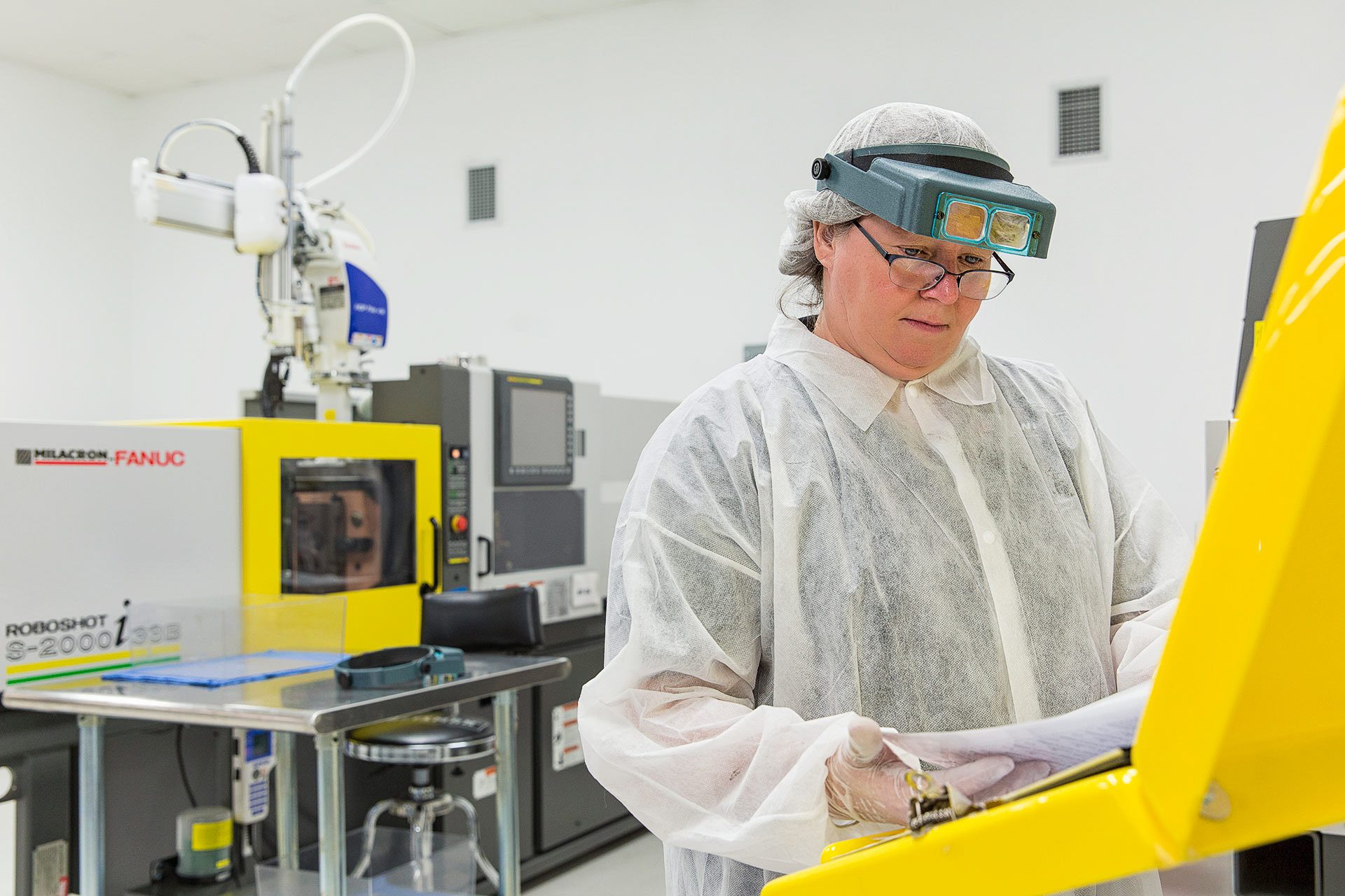 Industrial photography of an operator in clean-room gear inside an Orlando facility.