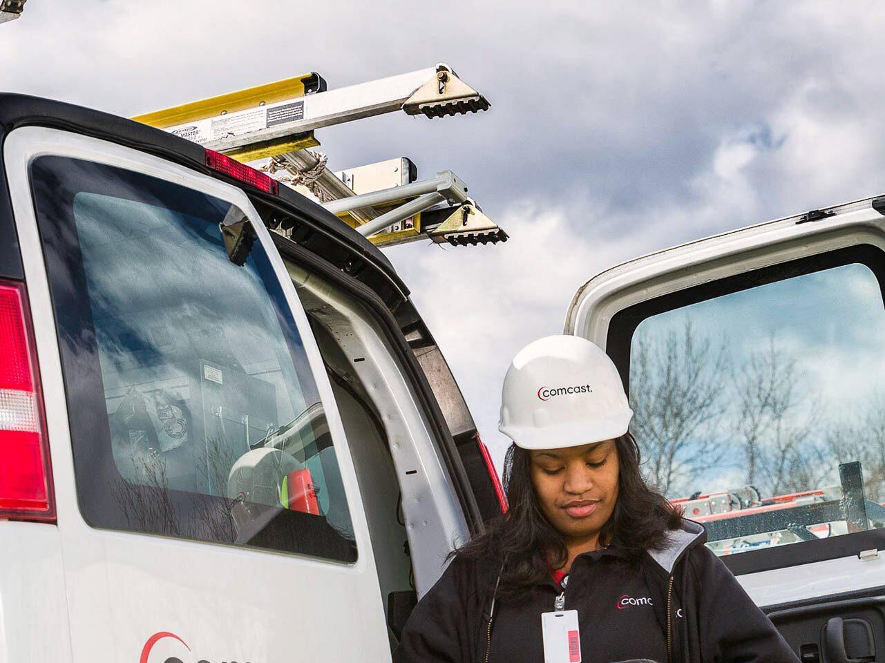 Comcast service technician working with handheld device outside company van - corporate photography Tampa.