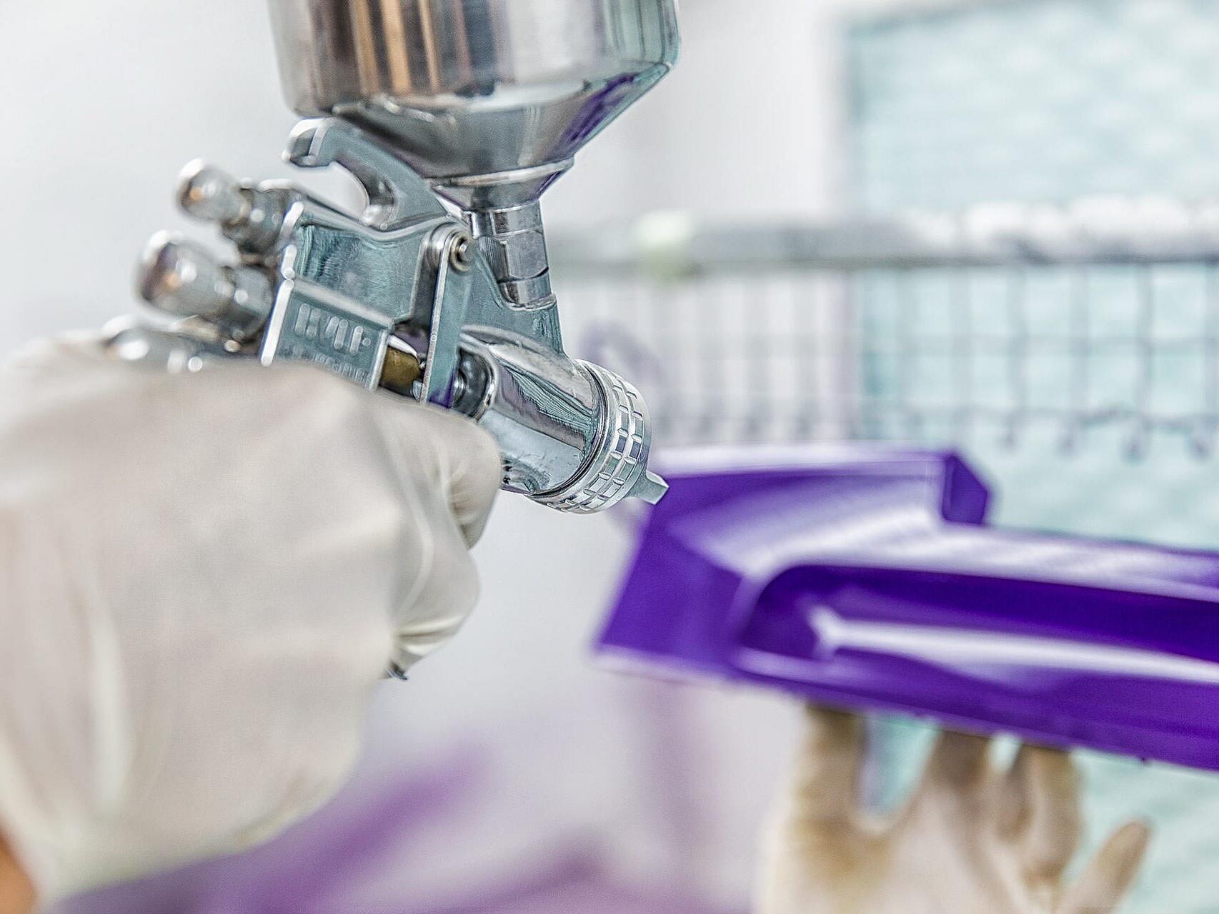 Spray-painting plastic components in factory - commercial production photography Tampa.