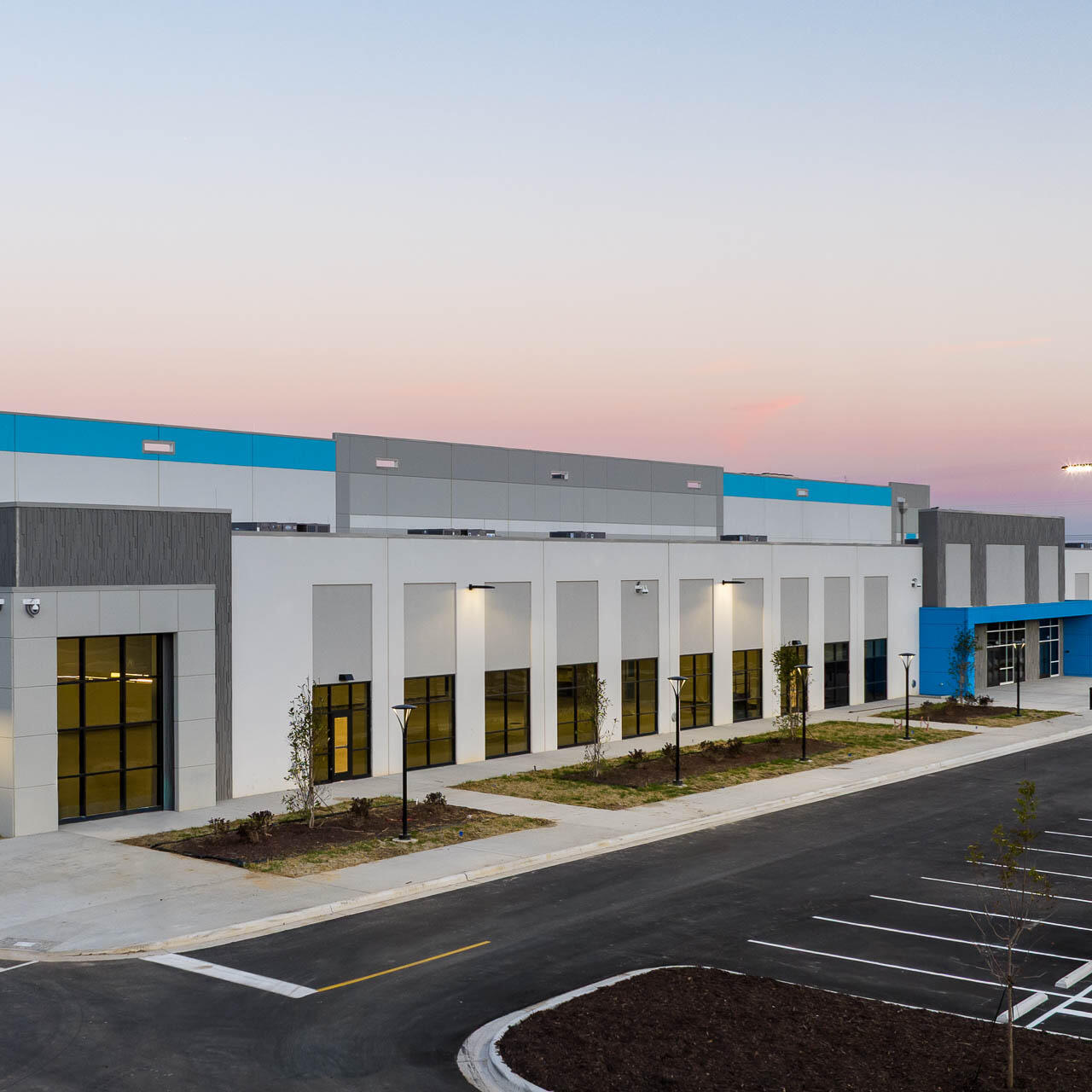 Aerial drone photograph of an Amazon fulfillment center at dusk showing modern architecture and exterior lighting near Tampa, Florida.