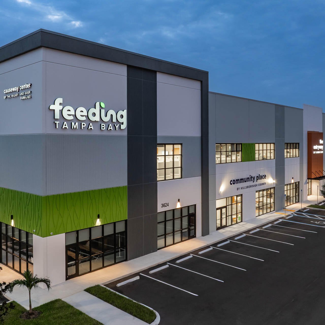 Aerial drone photograph of the newly constructed Feeding Tampa Bay facility at dawn showing modern architecture and illuminated signage.