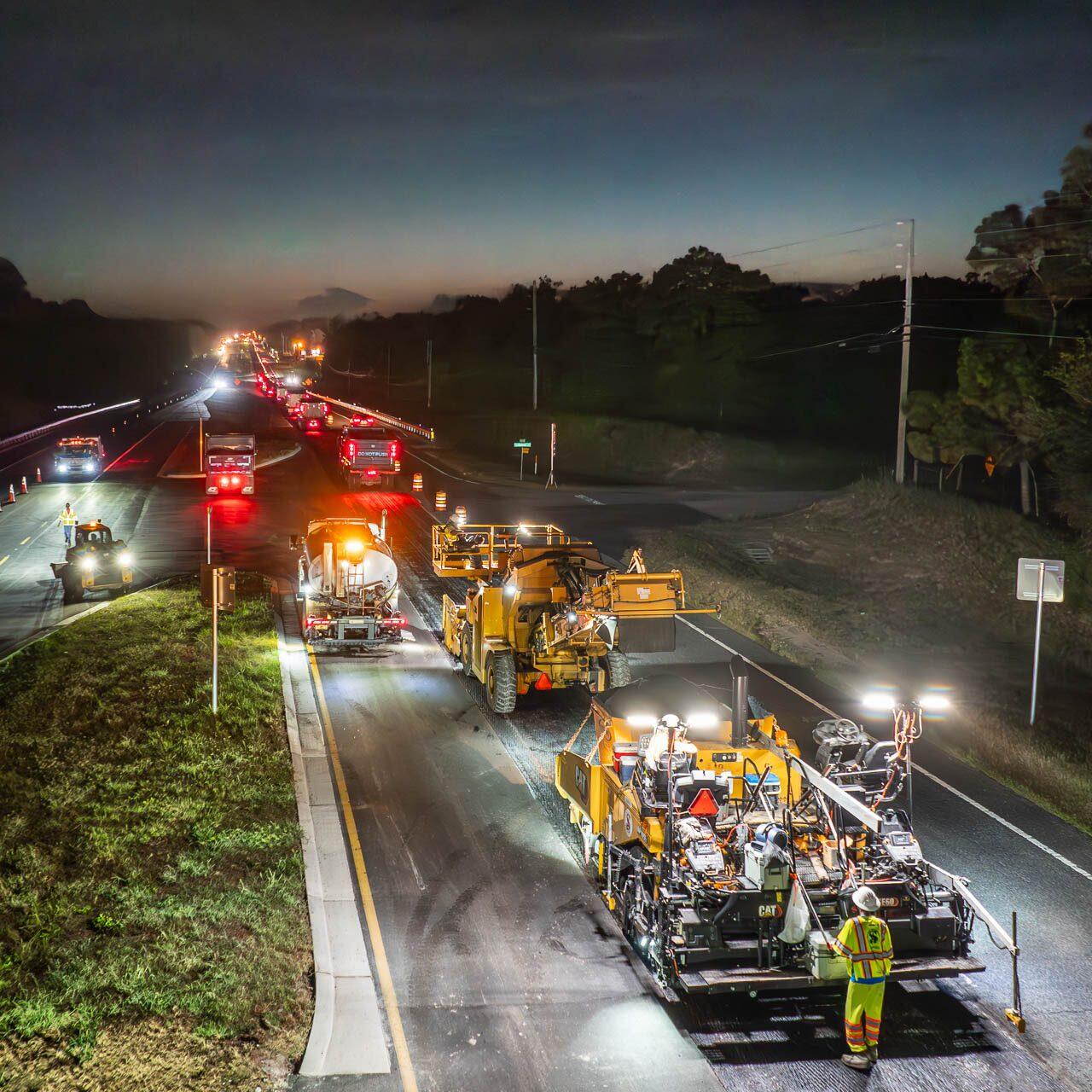 Aerial drone photograph of a nighttime highway construction crew resurfacing a road under work lights near Tampa, Florida.