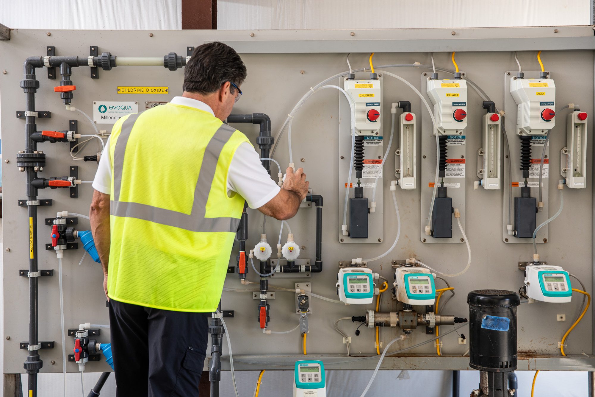 Technician servicing chemical feed system and dosing equipment at treatment facility - utility process photography