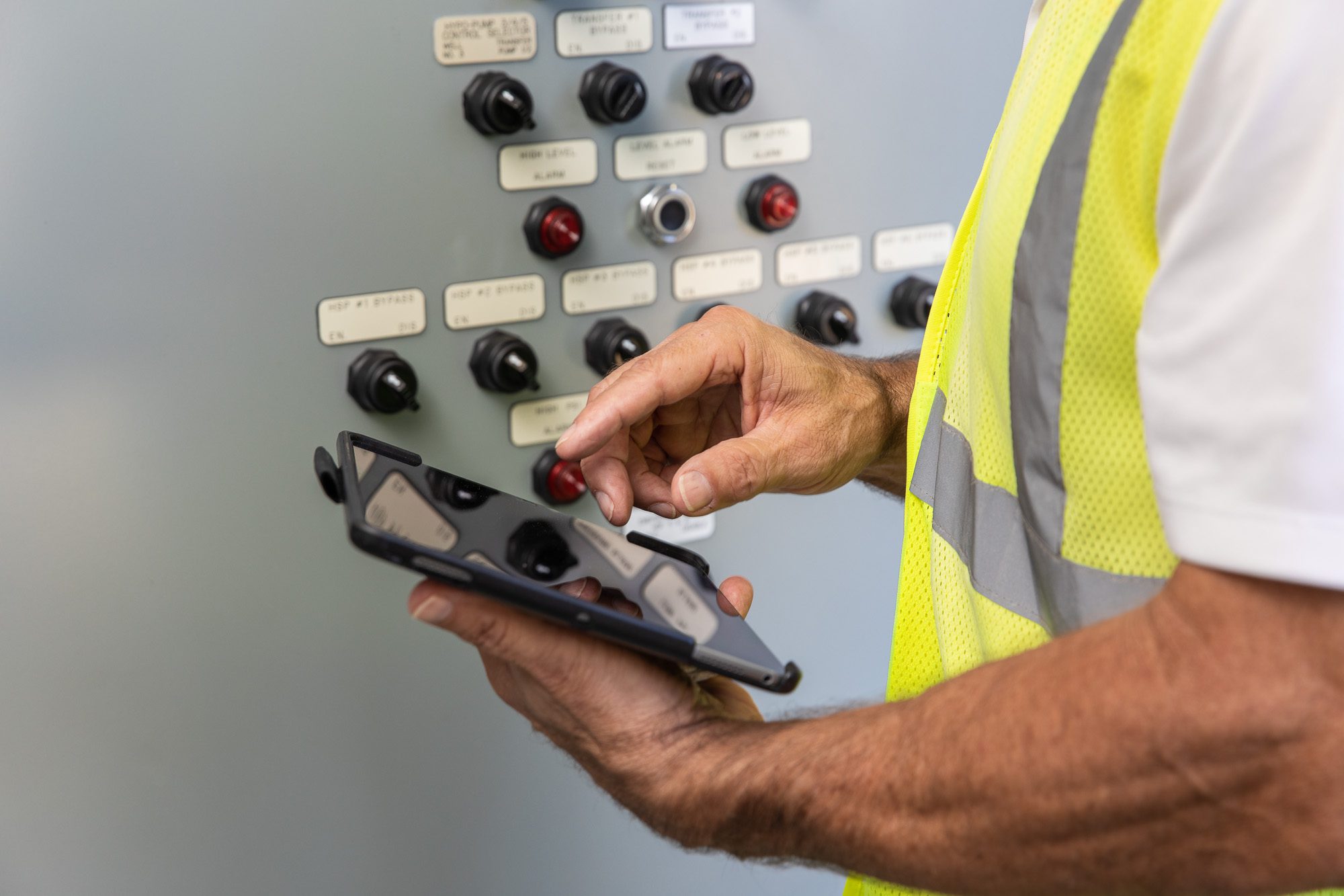 Technician using handheld controller for system monitoring at water facility - industrial workflow photography