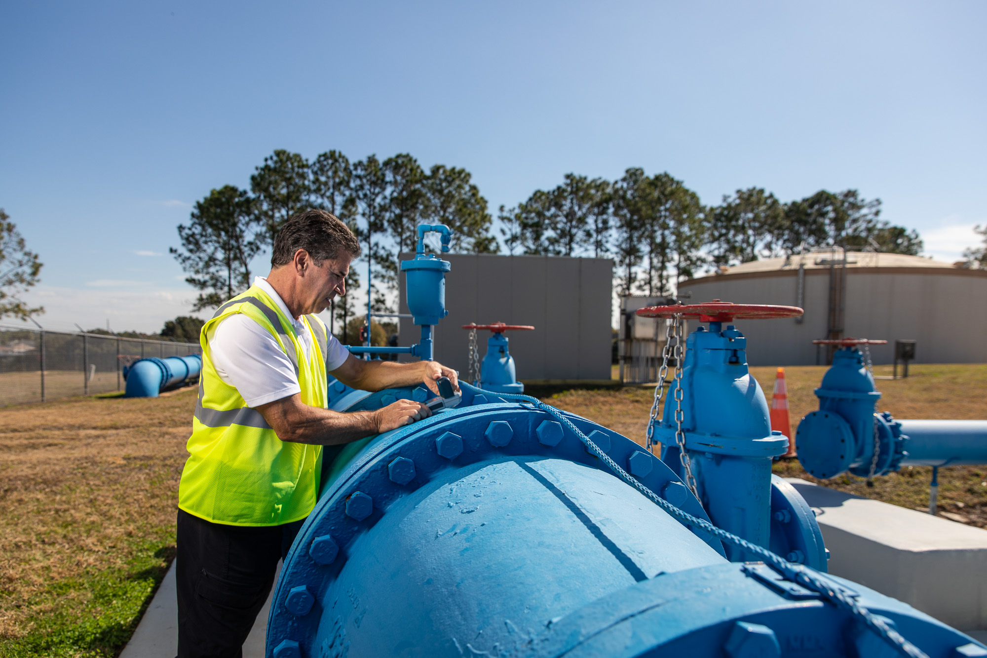 Technician operating large blue valve at water distribution system - field operations photography Florida