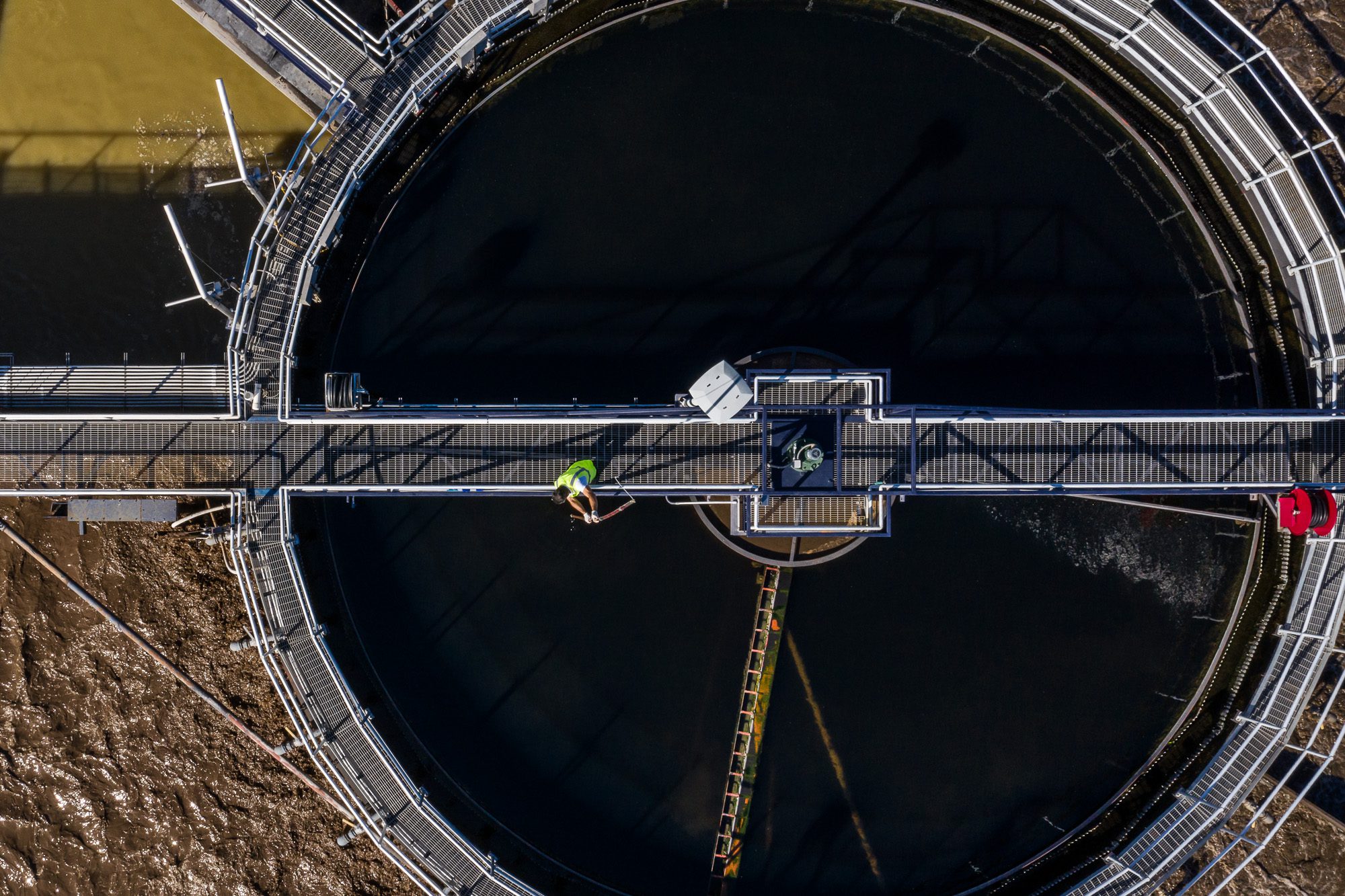 Aerial view of circular clarifier basin at water treatment facility with technician inspection - utility infrastructure photography Florida