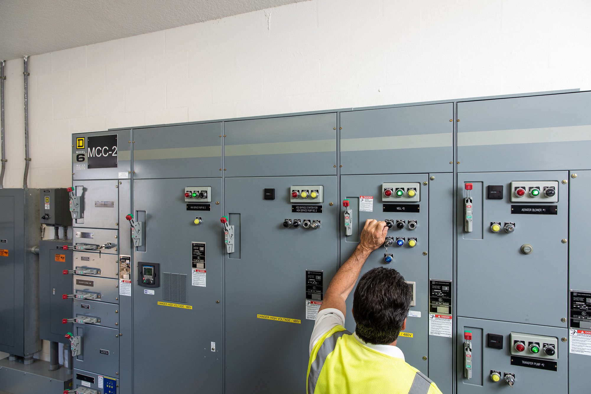 Electrical control panels and technician adjusting system settings at utility facility - infrastructure documentation photography