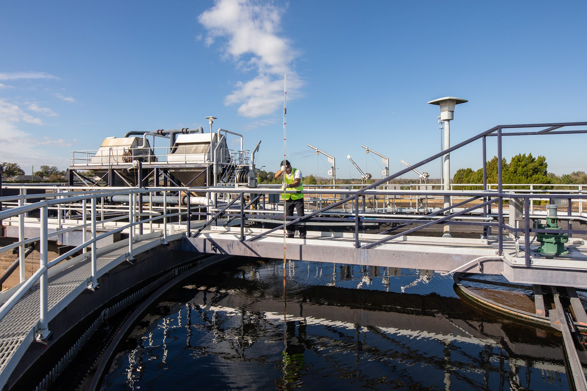 Water treatment clarifier walkway with technician collecting sample - municipal utility photography Florida